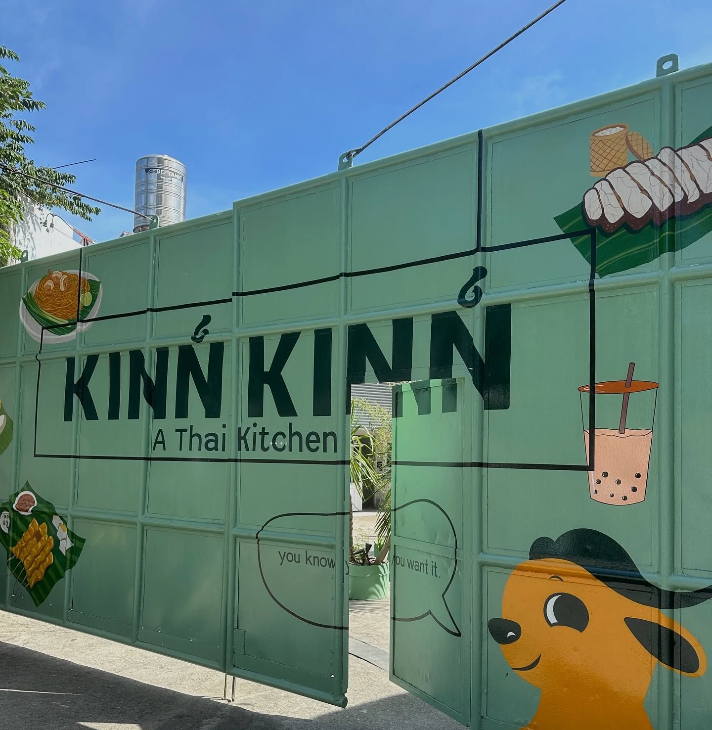 The painted green shipping container wall with the Kinn Kinn wordmark